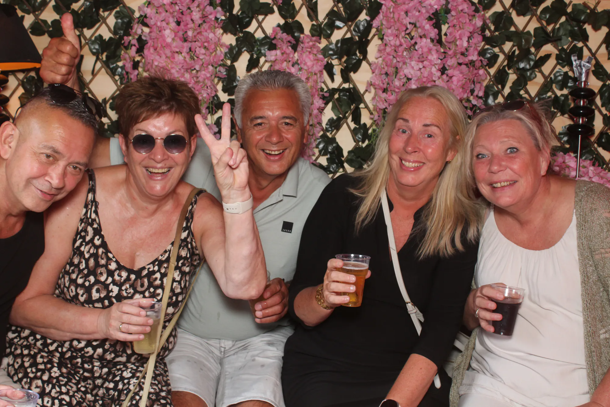 Gasten poseren voor de bloemenwand in de photobooth